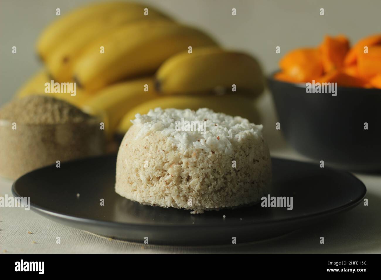 Tortino di farina di miglio al fuoco o puttu di miglio al fienile al vapore servito con fette di mango e plantani. Una varietà di torta a vapore di riso Kerala con cortile Foto Stock