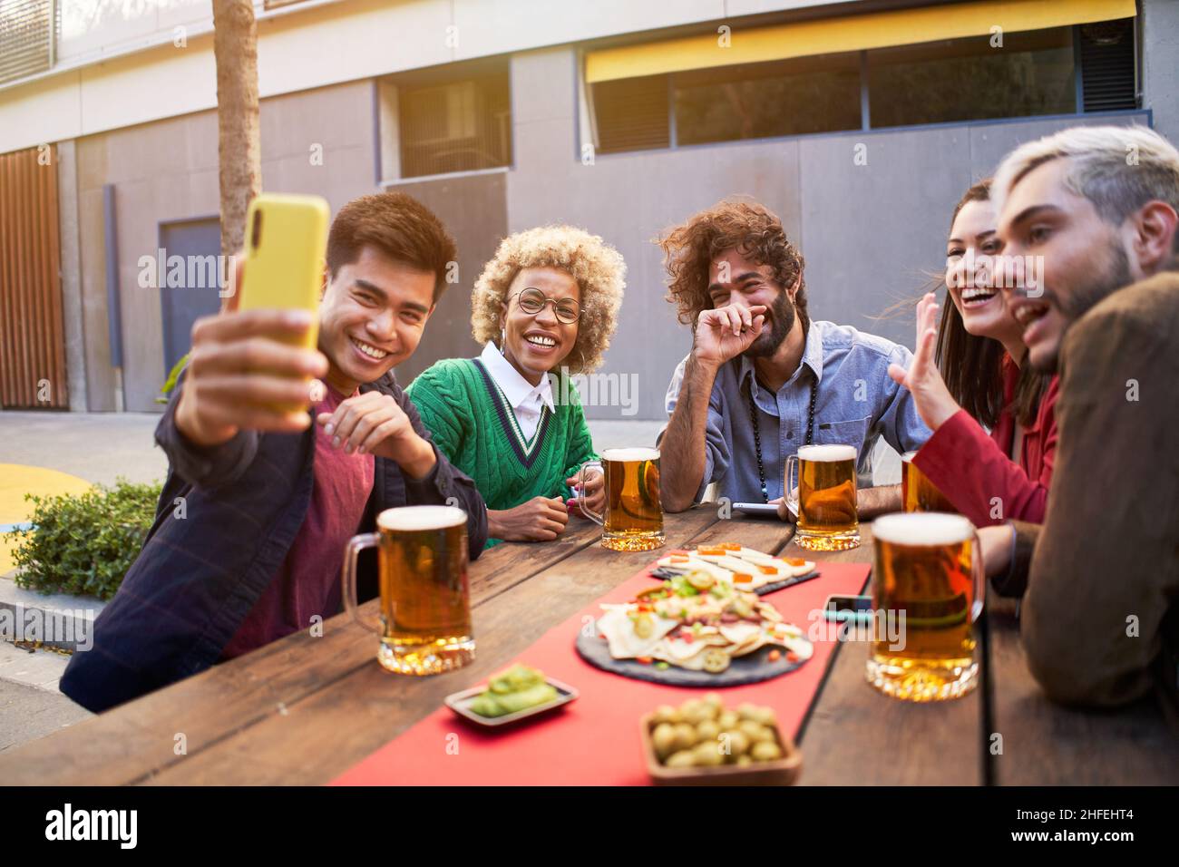 gruppo di amici multirazziali che prendono selfie sorridenti. con smartphone. Persone che si divertono all'aperto. Foto Stock