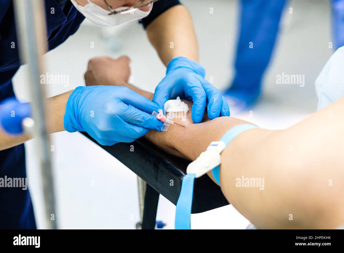Il medico inserisce un ago contagocce nel braccio del paziente. Messa a fuoco selettiva. Catetere per somministrazione endovenosa di farmaci in mano di una persona. Foto Stock