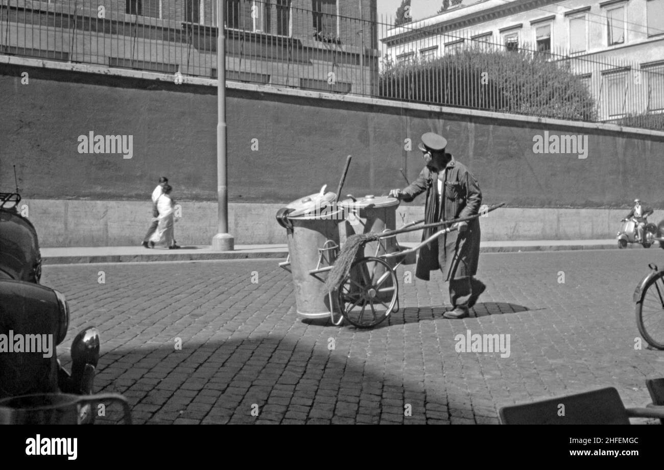 Una spazzatrice stradale a Roma, Italia c.1960. Il suo carrello porta una scopa che sembra molto simile al broomstick di una strega! Questa immagine proviene da una vecchia trasparenza amatoriale 35mm in bianco e nero – una fotografia d'epoca 1950/60s. Foto Stock