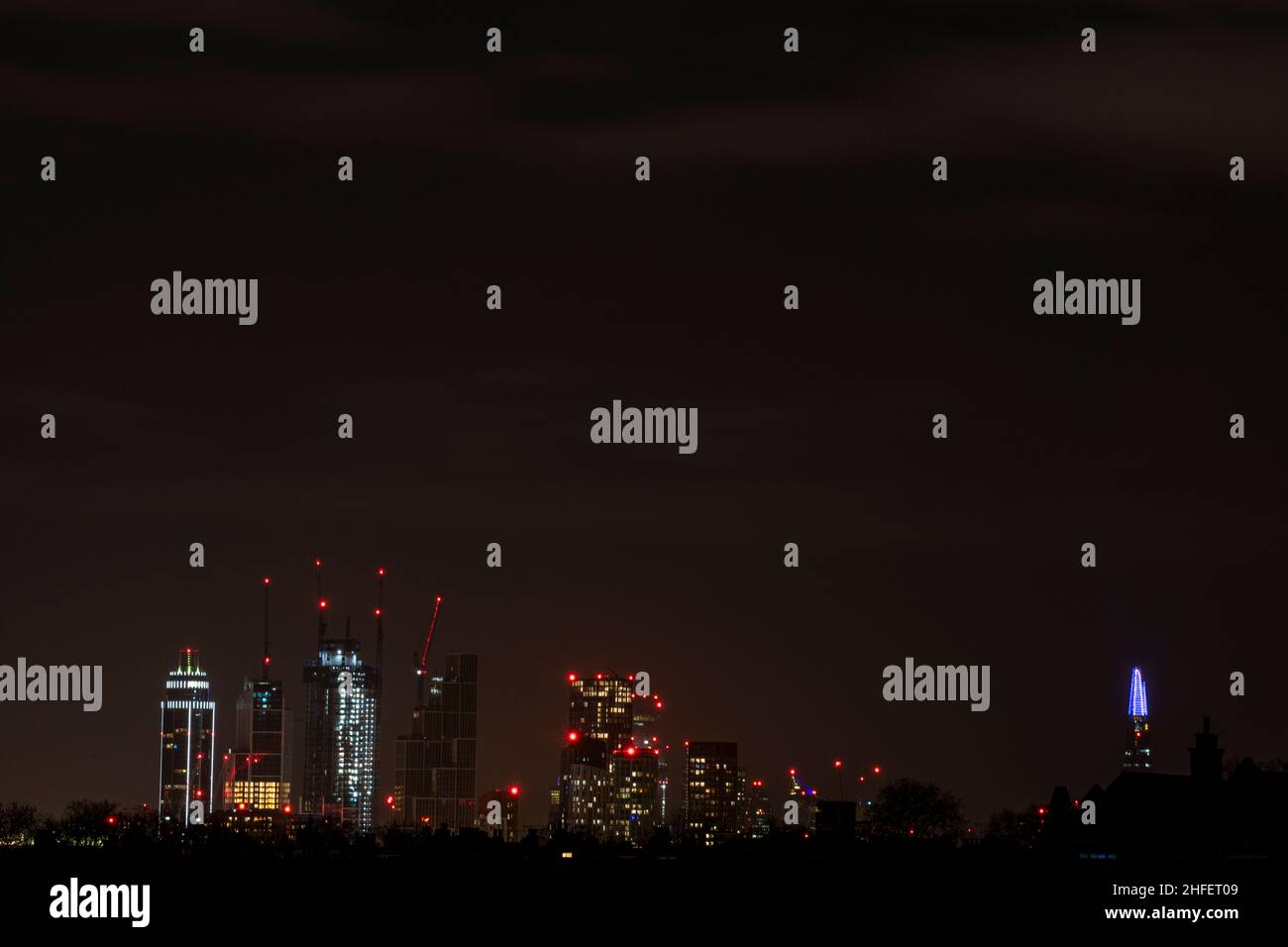 Gru e alti edifici, tra cui la St Georges Tower on Uno skyline di Londra di notte Foto Stock