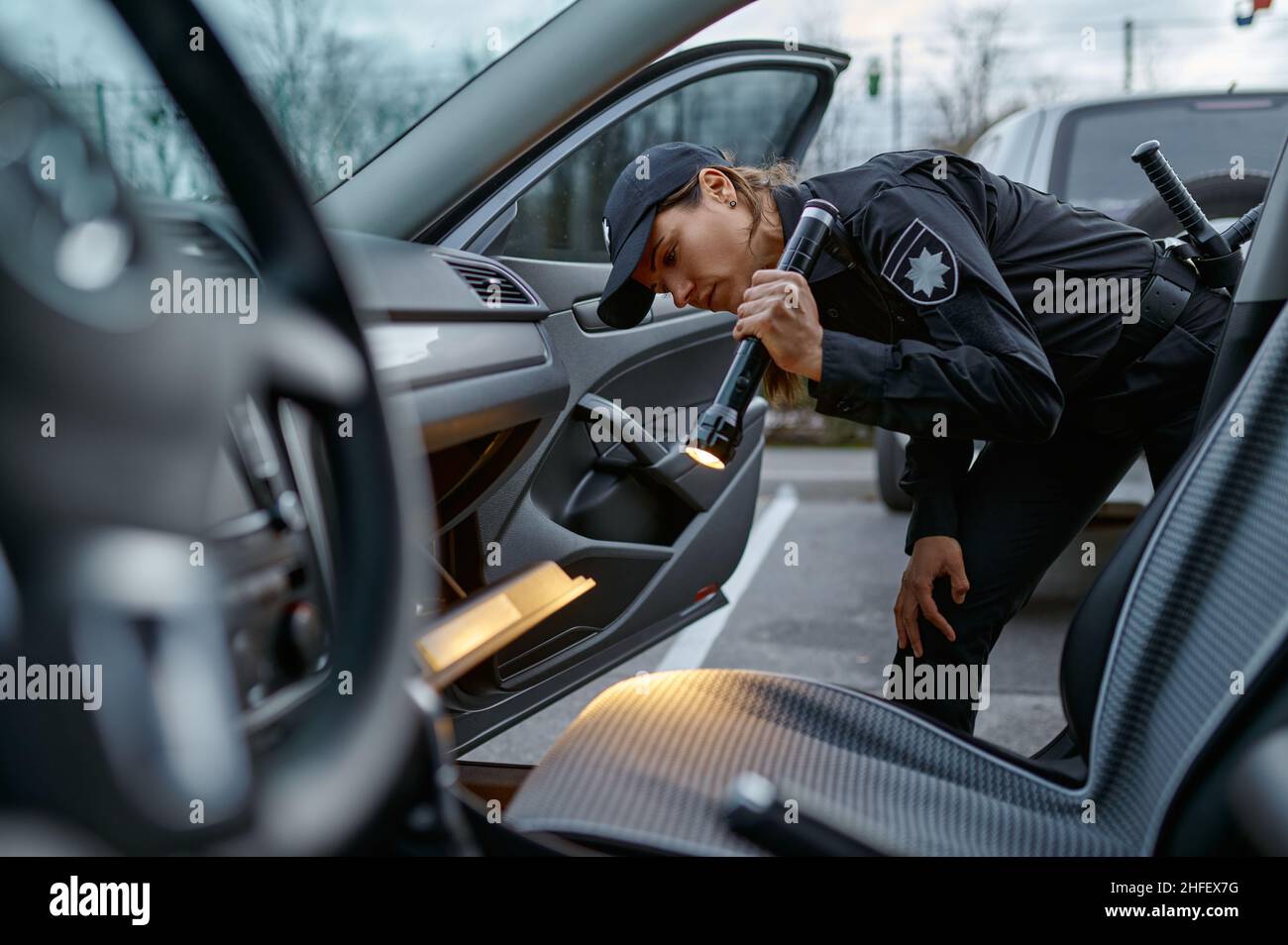 Donna poliziotto utilizzando torcia per l'esame di auto Foto Stock