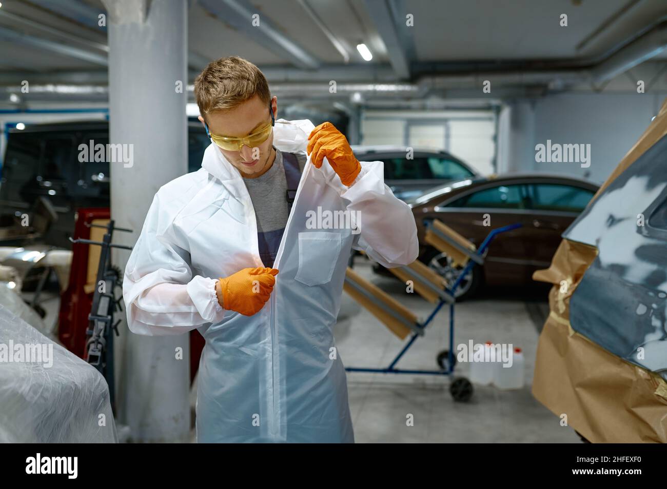 Il tecnico scollega il vestito protettivo dopo il lavoro di finitura Foto Stock