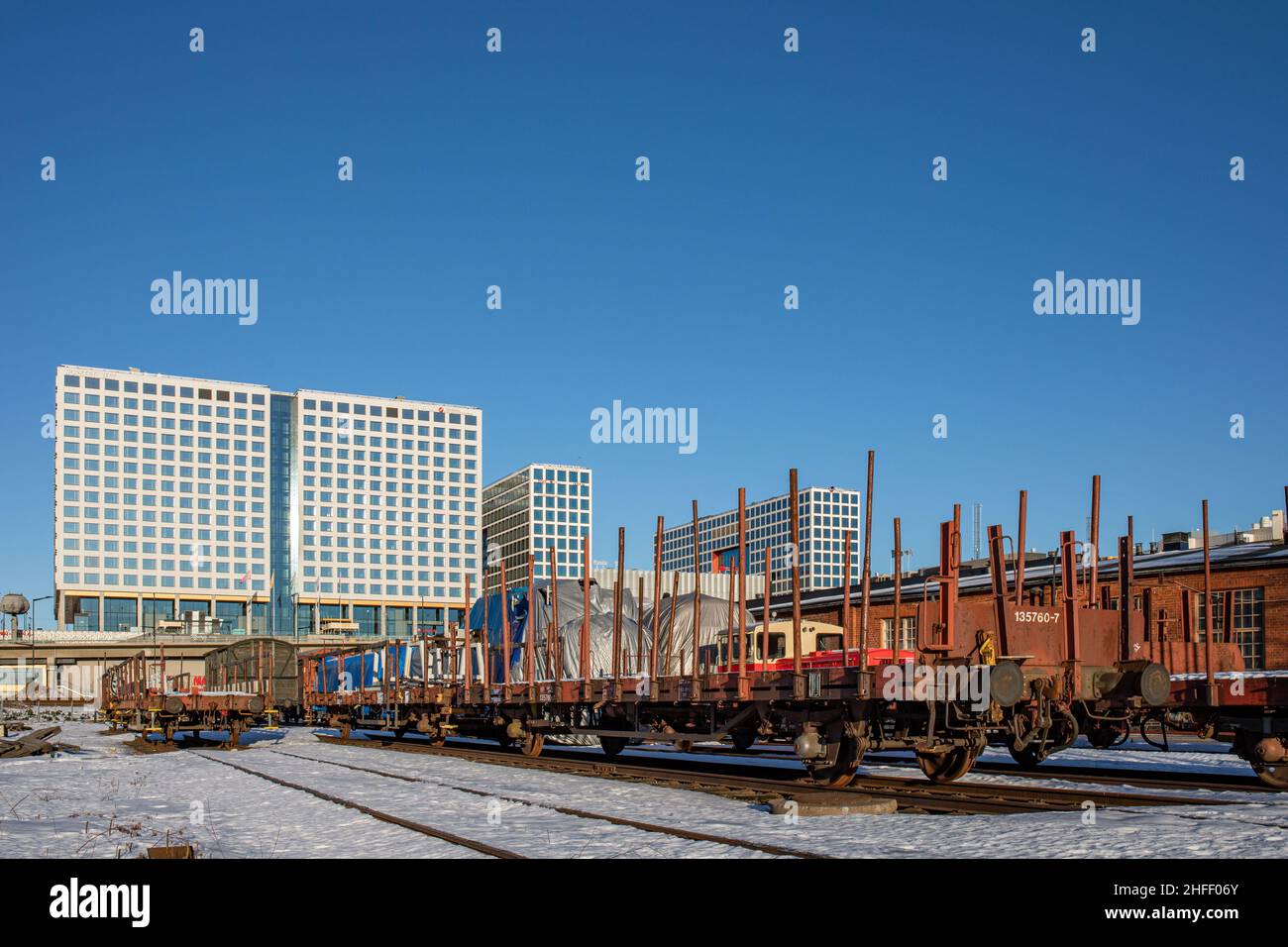 Vagoni piatti nel vecchio cantiere ferroviario con Mall of Tripla contro il cielo blu chiaro sullo sfondo nella giornata invernale di sole nel distretto di Pasila di Helsinki, Finlandia Foto Stock