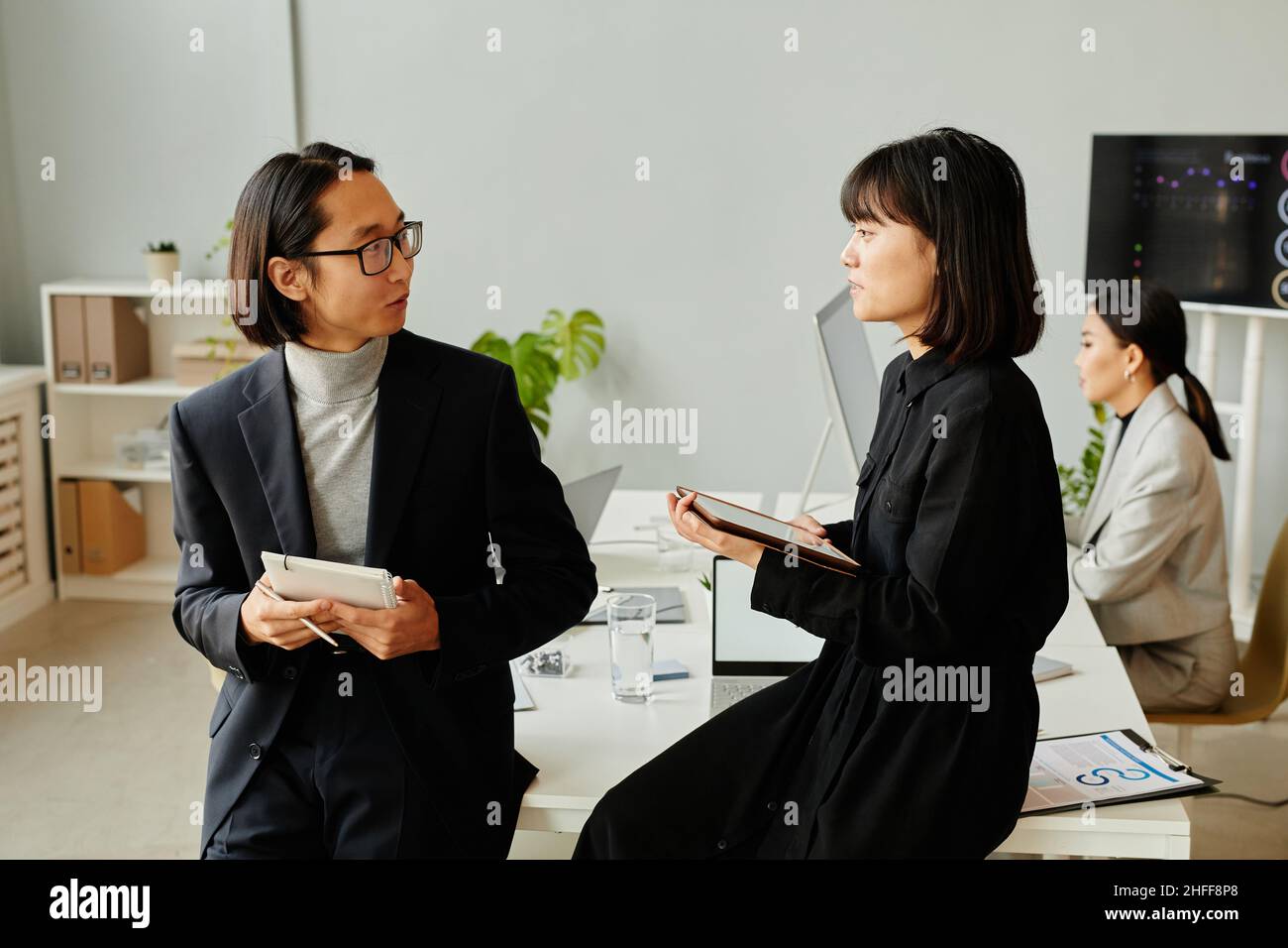 Ritratto di due uomini d'affari asiatici che indossano nero durante la discussione del progetto in ufficio Foto Stock