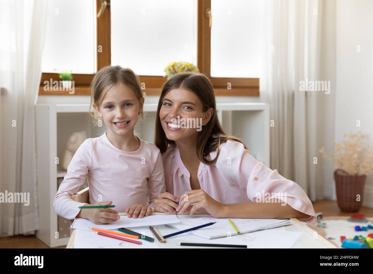 L'insegnante di arte la bambina distratta dal disegno posando alla macchina fotografica Foto Stock