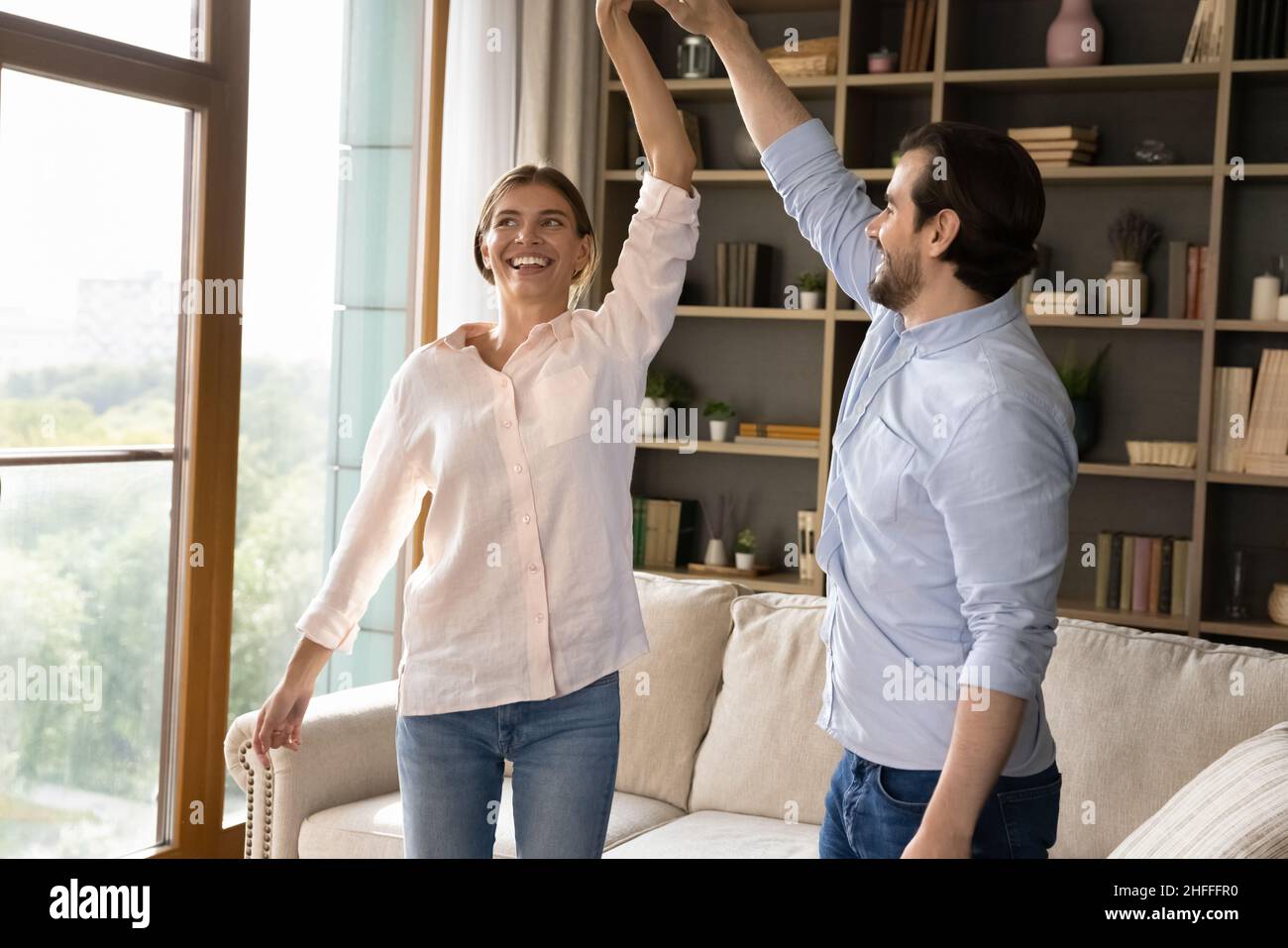 Giovane coppia che tiene le mani ballando alla musica favorita Foto Stock