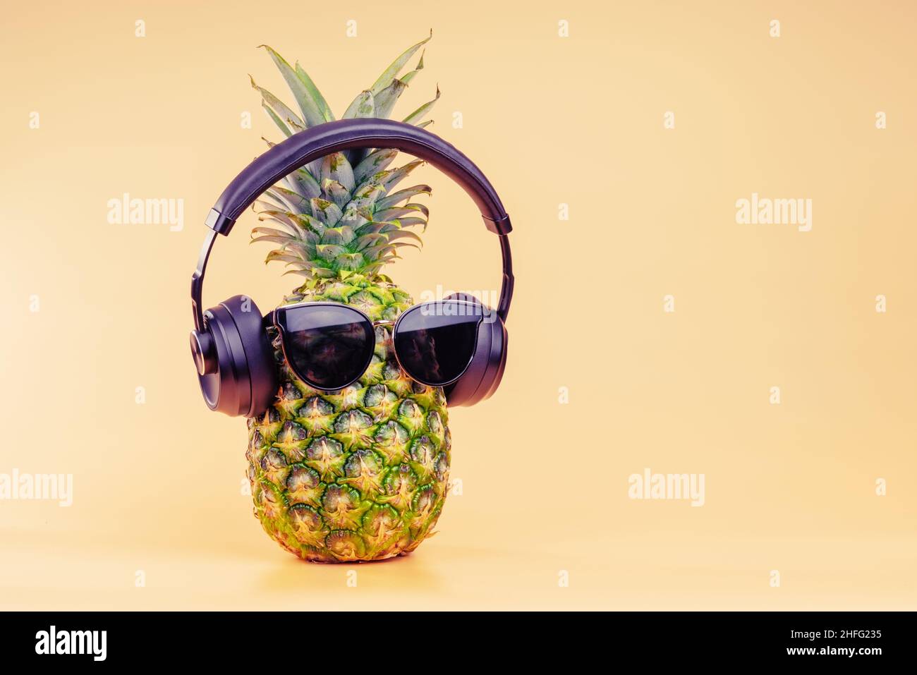 Idea creativa di un'immagine di ananas di una persona cuffie e occhiali come un turista rilassante in vacanza. Su sfondo giallo. Foto Stock