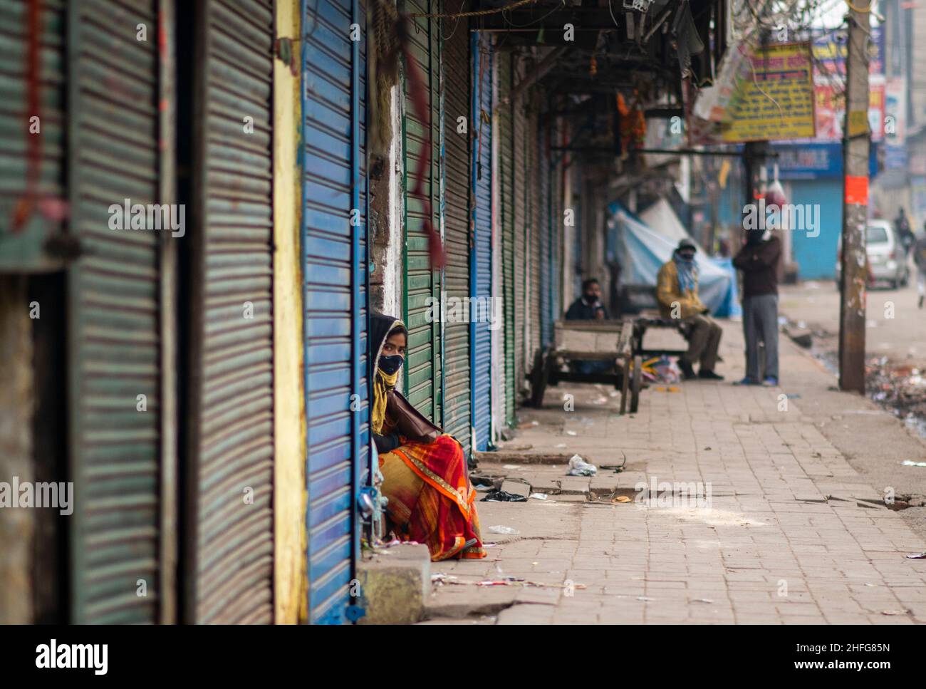 New Delhi, India. 16th Jan 2022. Una donna che indossa una maschera facciale passa attraverso le persiane chiuse di negozi a Sadar bazaar.a causa dei crescenti casi di Covid-19 a Delhi, il governo ha imposto coprifuoco fine settimana. Il ministro della Sanità di Delhi Satyendar Jain ha detto che il coprifuoco del fine settimana e le restrizioni preventive hanno contribuito a frenare la diffusione di Covid-19 nella capitale nazionale. Delhi ha riportato 20.718 casi di covid e 30 morti il 16th gennaio 2022, mentre il tasso di positività si è attestato al 30,64 per cento. Credit: SOPA Images Limited/Alamy Live News Foto Stock