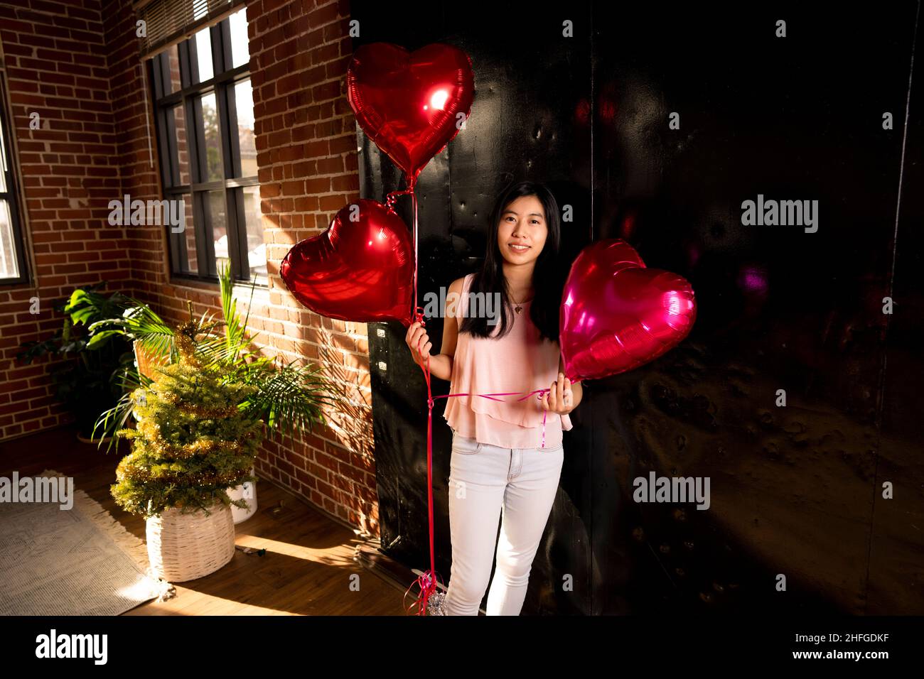 Giovane donna dell'Asia orientale che tiene le palloncini del cuore del giorno di San Valentino Foto Stock