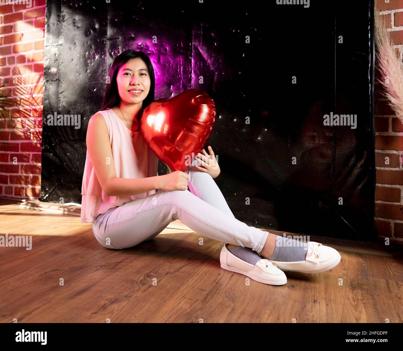 Giovane donna dell'Asia orientale che tiene le palloncini del cuore del giorno di San Valentino Foto Stock