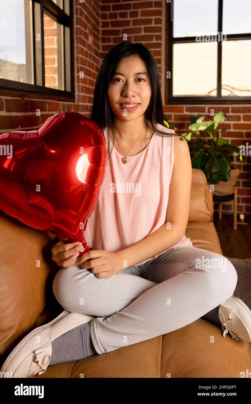 Giovane donna dell'Asia orientale che tiene le palloncini del cuore del giorno di San Valentino Foto Stock