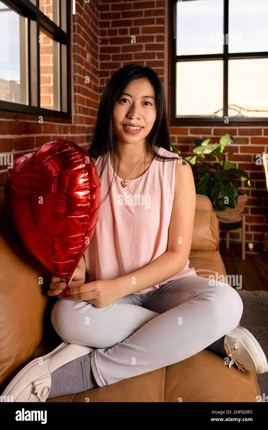 Giovane donna dell'Asia orientale che tiene le palloncini del cuore del giorno di San Valentino Foto Stock