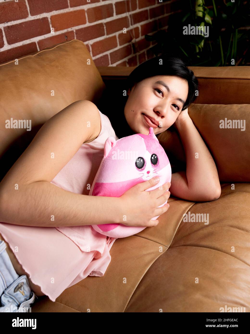 Giovane donna asiatica orientale che tiene Valentines rosa Plush Kitten Pillow Foto Stock