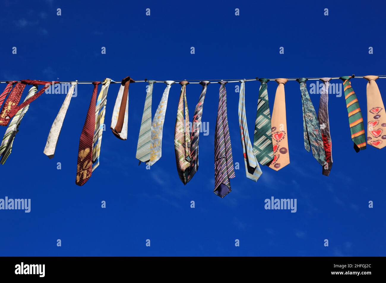 Viele bunte Krawatten hängen an einer Wäscheleine, blauer Himmel / molti legami colorati appesi su un clothesline, cielo blu Foto Stock