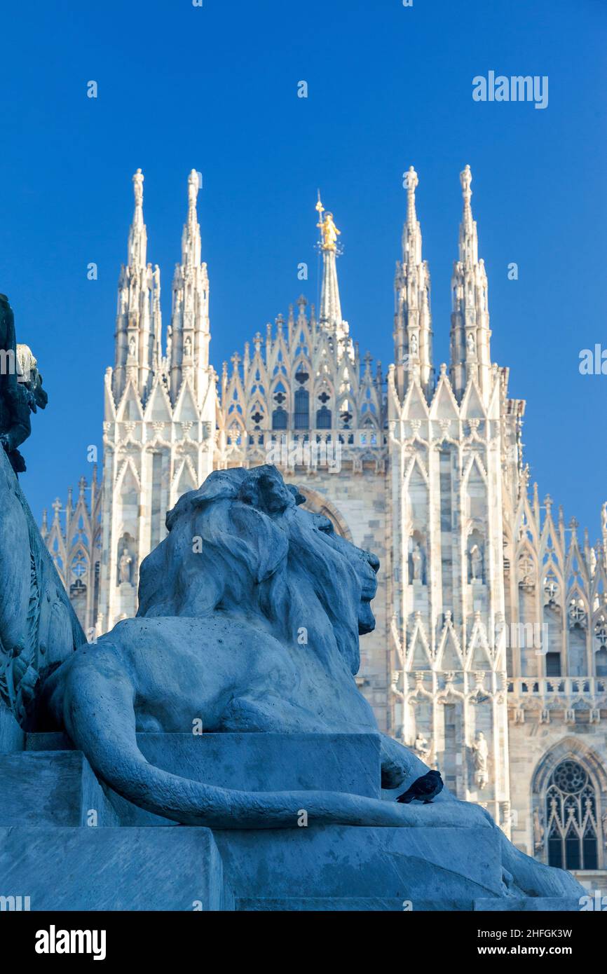 Piazza del Duomo, la piazza più famosa di Milano. In primo piano, il leone alla statua di Vittorio Emmanuelle e alle spalle il Duomo di Milano Foto Stock
