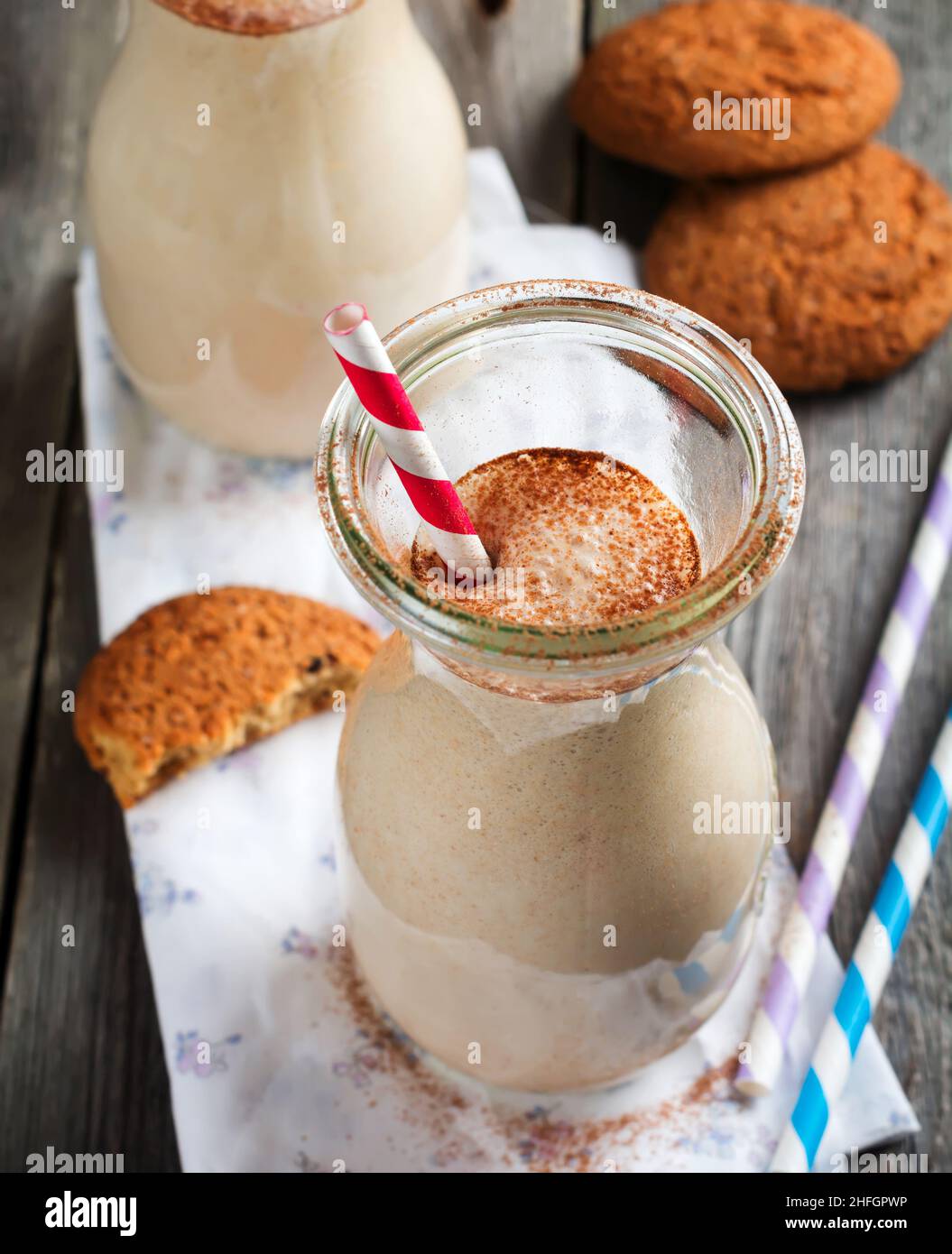 Frullati alla vaniglia al latte con biscotti di farina d'avena in vasetti di vetro sul vecchio sfondo di legno. Messa a fuoco selettiva. Foto Stock