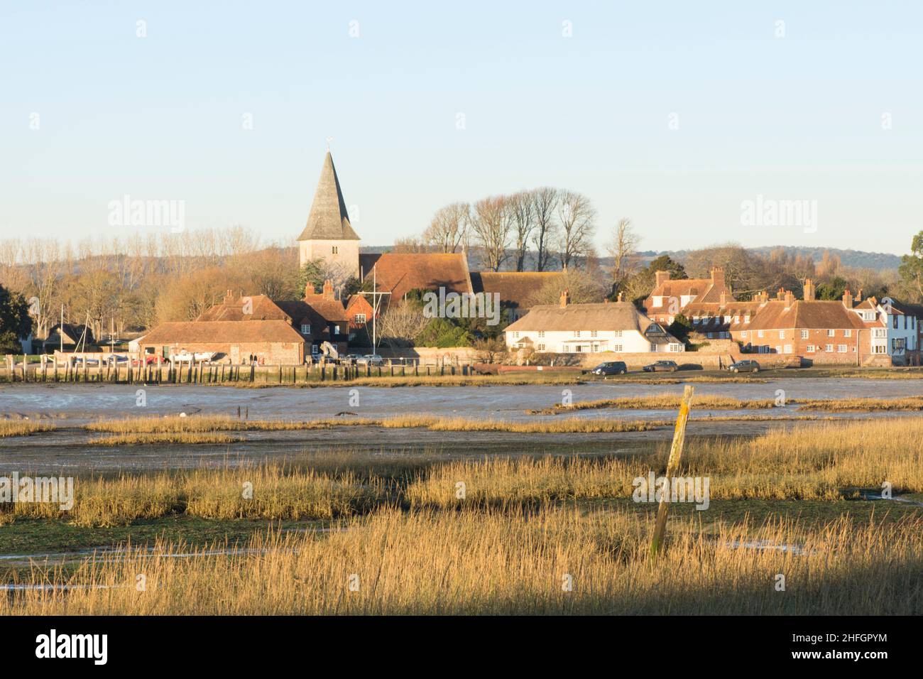 Bosham villaggio e la chiesa vista su mudflats e erbe, marea fuori. Sunny, blue, Chichester Harbour, West Sussex, Inghilterra, REGNO UNITO. Gennaio Foto Stock
