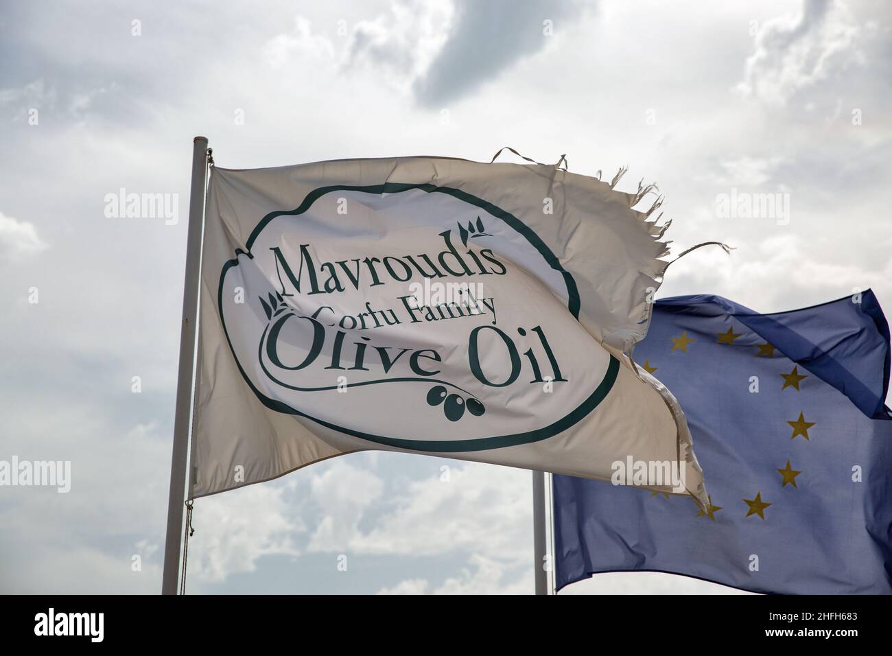 Vraganiotika, Corfù, Grecia - 05 agosto 2021: Famoso Mavrodius fabbrica di produzione di spremitura olio d'oliva e museo bandiera closeup onding. Foto Stock