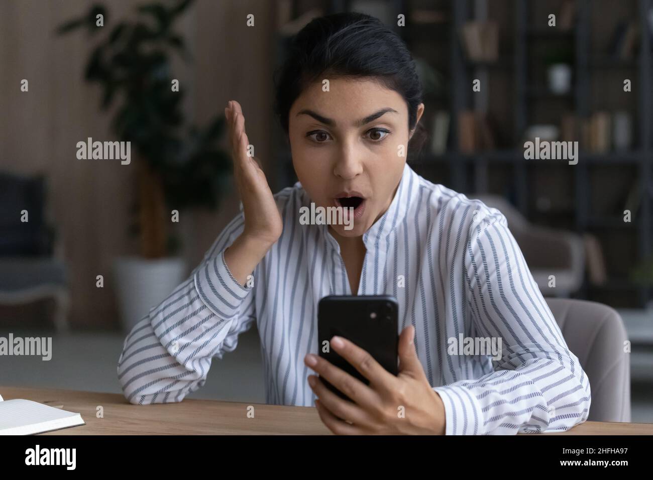 Sorpresa giovane indiana che guarda lo schermo del cellulare. Foto Stock