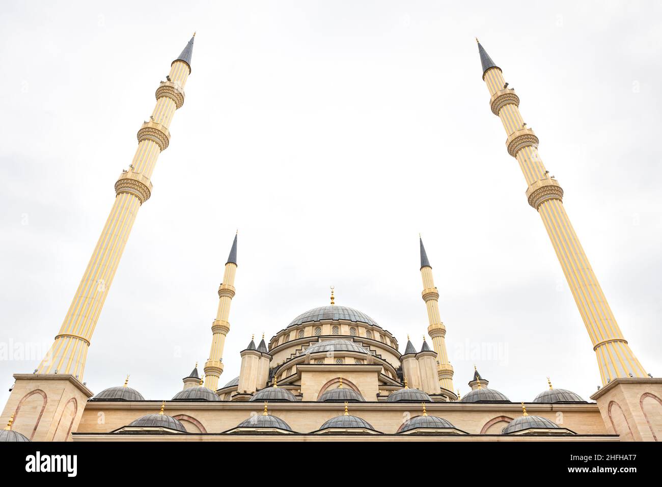 Minareti beige di moschea contro cielo nuvoloso grigio. L'Islam è la religione del mondo, la fede in Dio. Simmetria nell'architettura. Spazio di copia. Il cuore della Cecenia Foto Stock