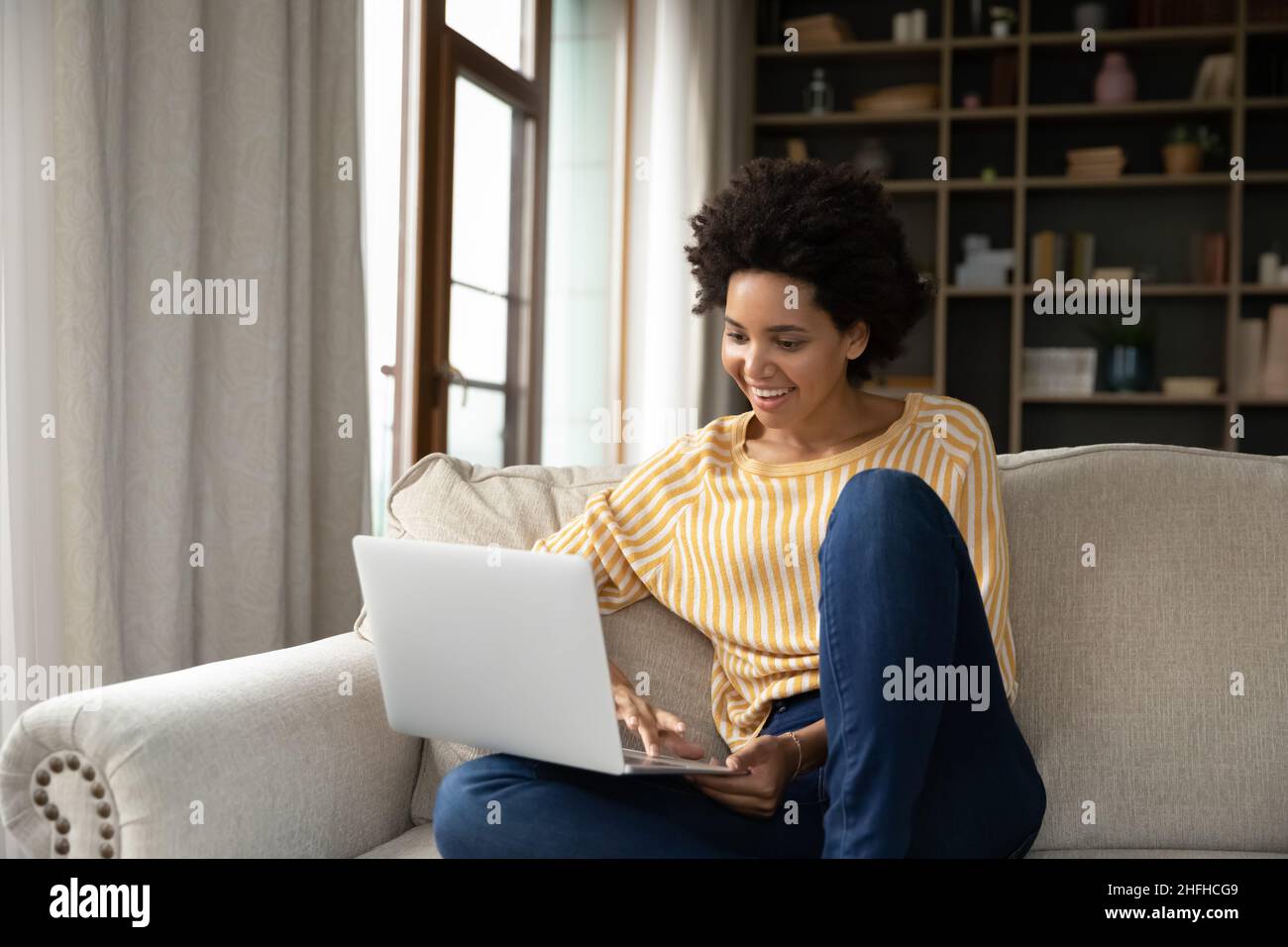 Felice bella millenaria donna afroamericana usando il computer. Foto Stock