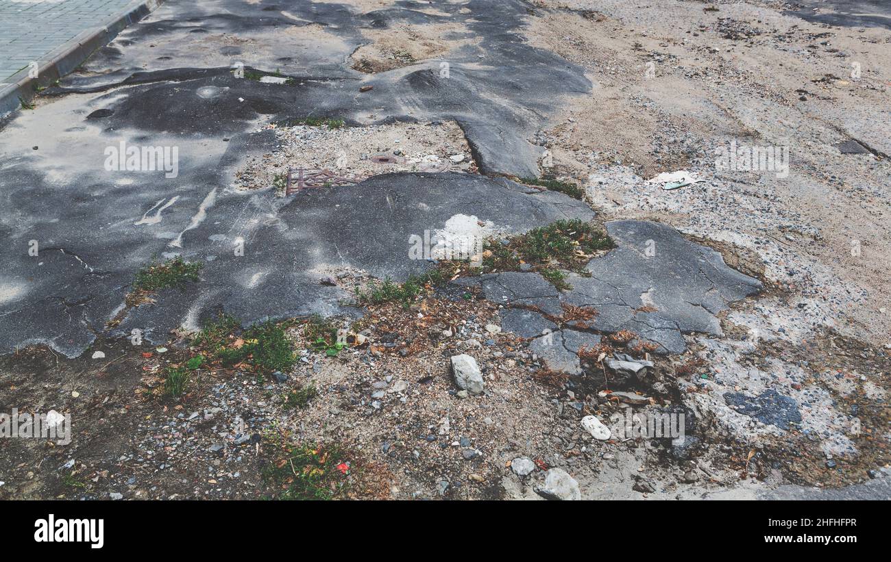 Una strada danneggiata da pioggia e neve, che necessita di manutenzione. Pavimentazione asfaltata rotta con conseguente buche, pericolosa per i veicoli. Foto Stock