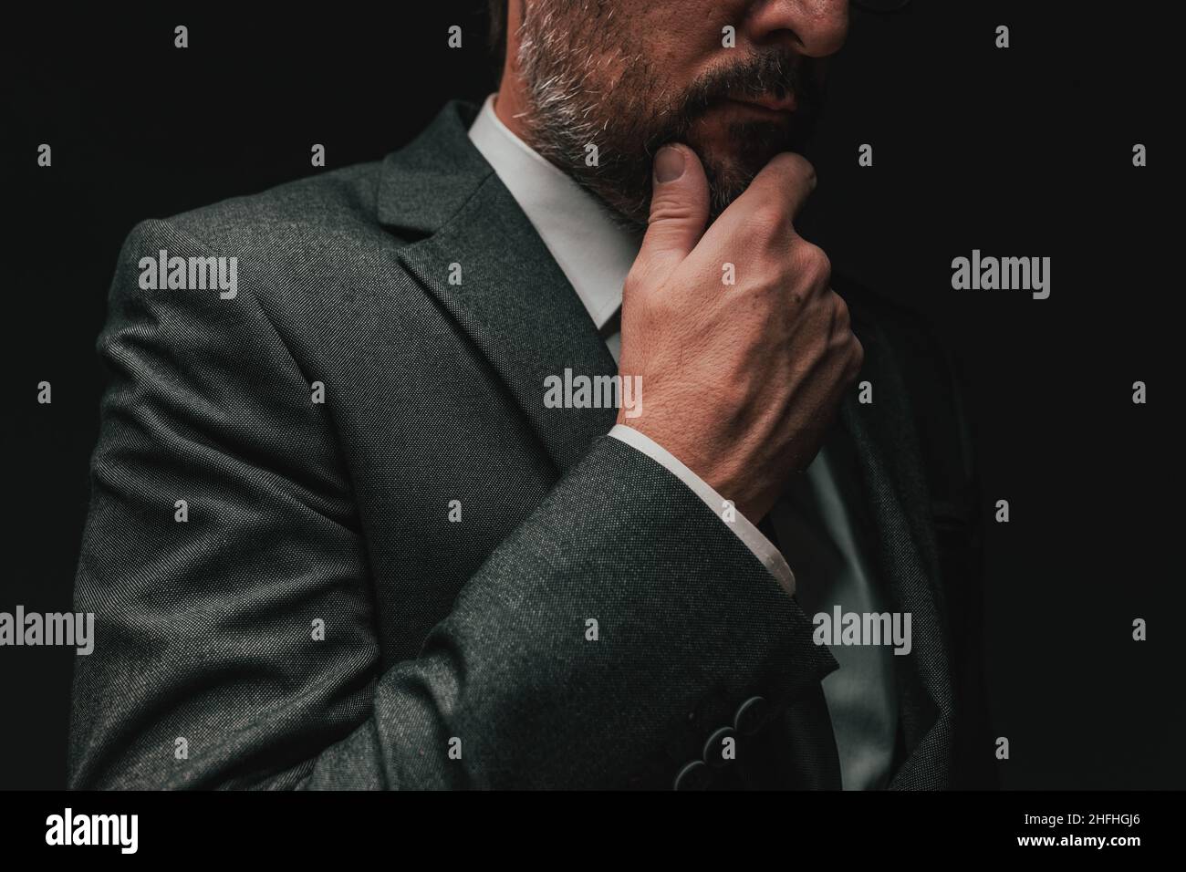 Considerazione prima di iniziare un business, uomo d'affari elegante in grigio vestito pensiero e pianificazione, basso ritratto chiave con fuoco selettivo Foto Stock