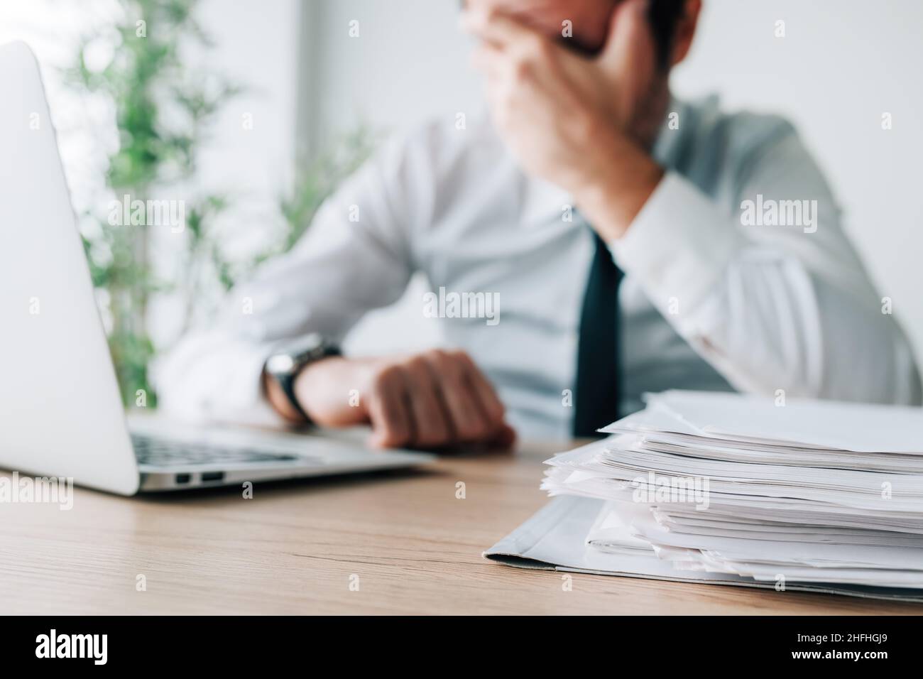 Fallimento di carriera, deluso uomo d'affari che copre il volto in ufficio mentre si siede alla scrivania, fuoco selettivo Foto Stock