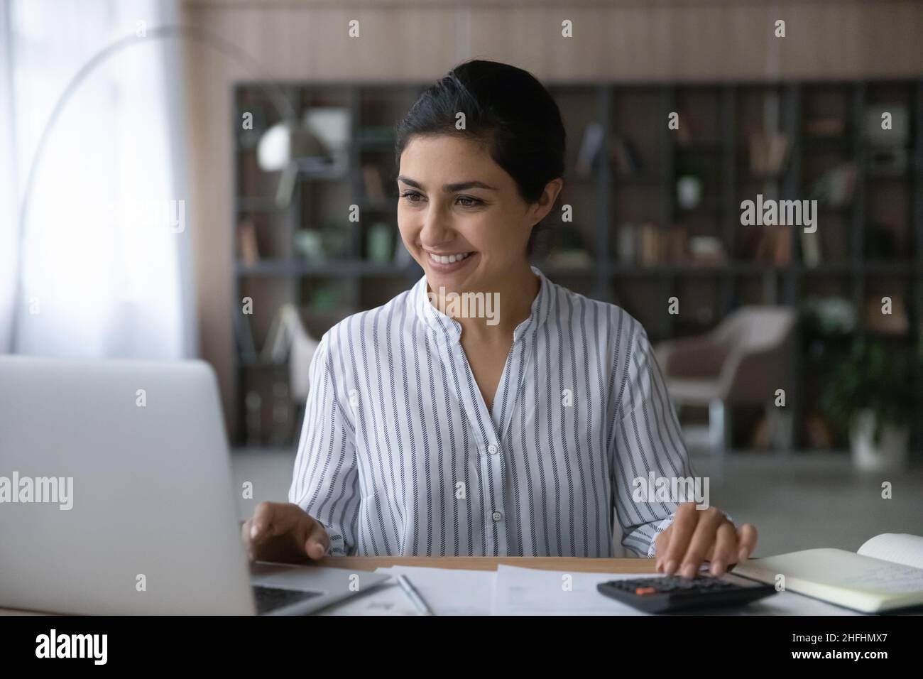 Felice giovane donna indiana che gestisce il budget mensile. Foto Stock