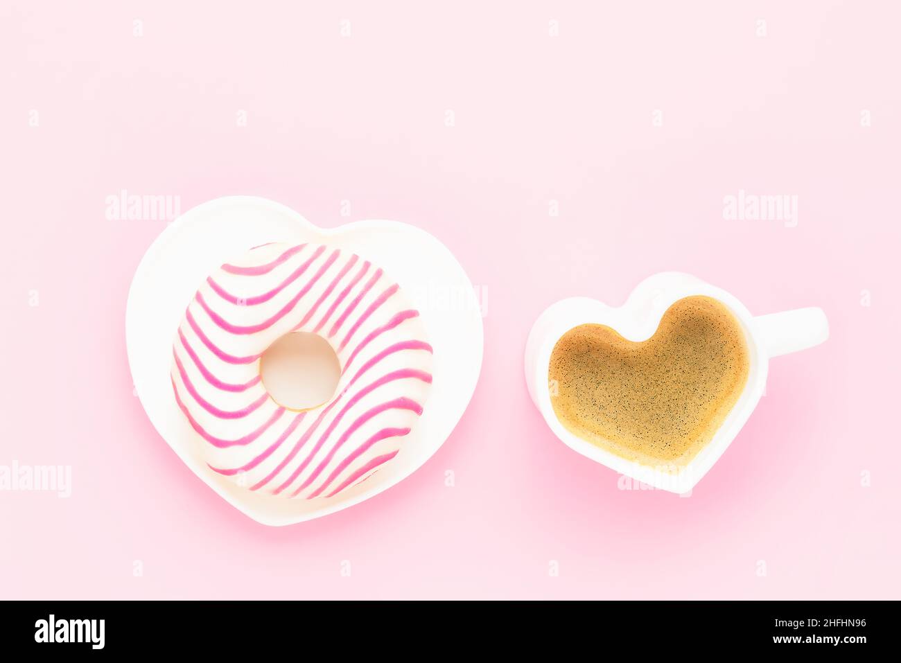 Tazza di caffè e ciambella rosa nella piastra a forma di cuore. Concetto di San Valentino. Vista dall'alto, spazio di copia per il testo. Foto Stock
