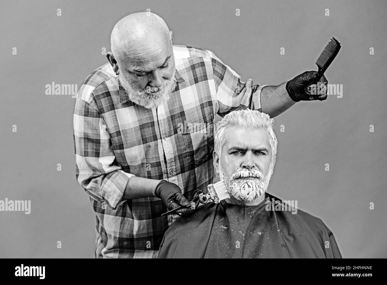 Colorazione dei capelli in colore grigio. Parrucchiere applicazione di tinta colorata su uomo modella capelli. Pubblicità e concetto di barbiere. Professionale Foto Stock