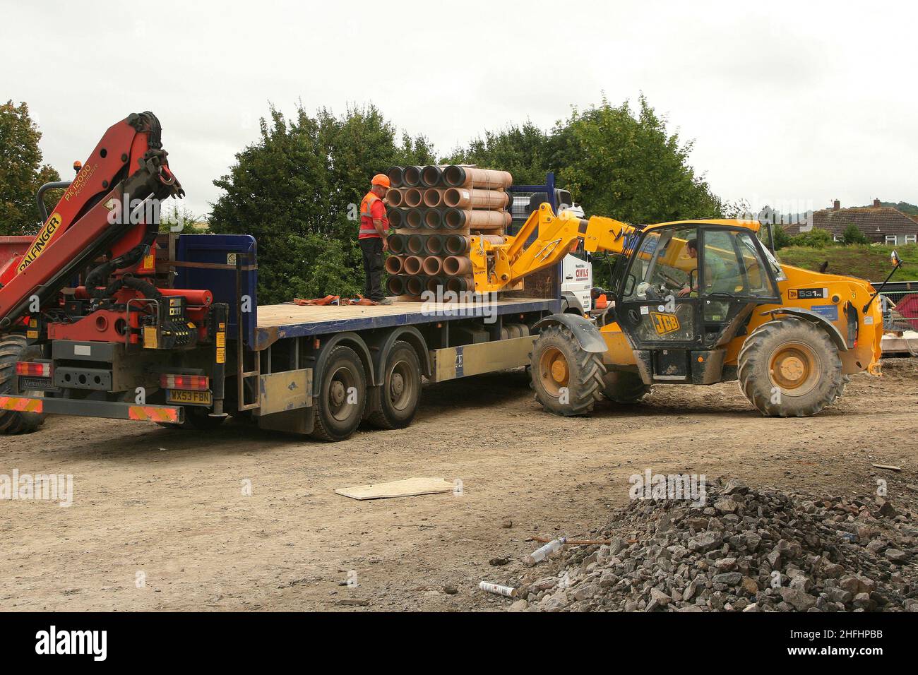 Luglio 2007 - costruzione movimentatore telescopico carrello elevatore scarico di un grande camion di tubi di argilla su un cantiere. Foto Stock