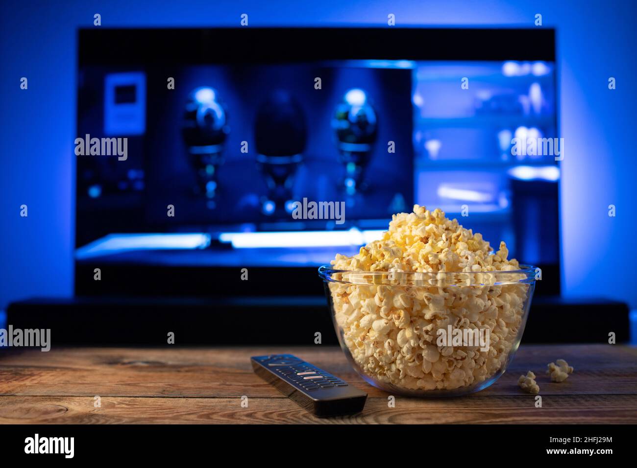 Una ciotola di vetro di popcorn e il telecomando in background il  televisore funziona. Serata accogliente guardando un film o una serie TV a  casa Foto stock - Alamy