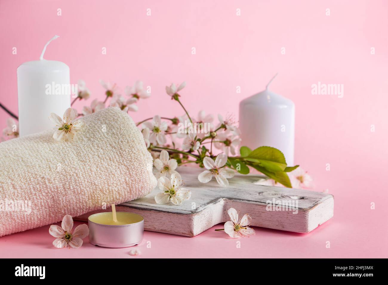 Prodotti cosmetici naturali per spa e aromaterapia. Concetto di relax. Candele, fiori e un asciugamano su sfondo rosa. Inserire il testo. Foto Stock