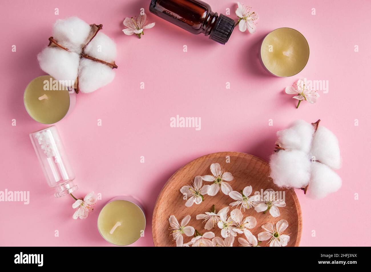 Cura della pelle, spa e concetto di aromaterapia. Prodotti cosmetici naturali su sfondo rosa. Aroma candele e fiori per relax e yoga. Luogo per Foto Stock