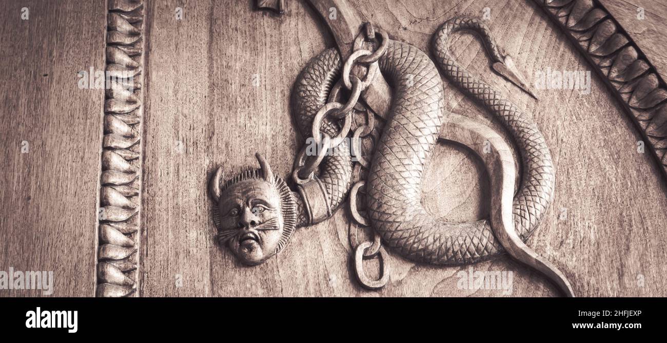 Serpente diavolo simbolo. Fantasia creatura magica su una vecchia porta, 12th secolo Abbazia, Italia. Foto Stock