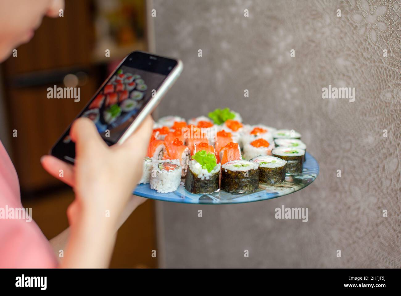 Preparazione di sushi e panini a casa. Sushi con frutti di mare, insalata e riso bianco. Cibo per la famiglia e gli amici. Una ragazza scatta le immagini sul suo telefono di un insieme di Foto Stock