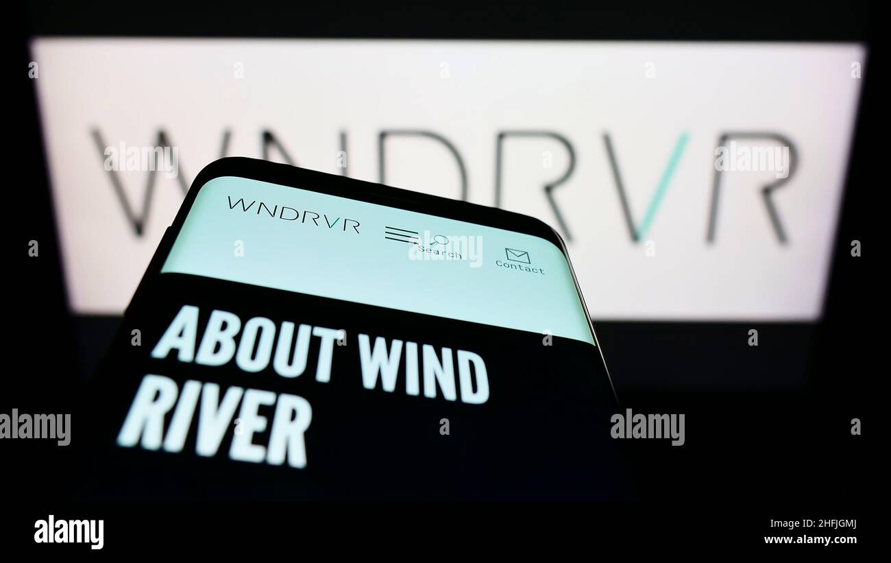 Telefono cellulare con sito web della società di software statunitense Wind River Systems Inc. Sullo schermo di fronte al logo aziendale. Mettere a fuoco sulla parte superiore sinistra del display del telefono. Foto Stock
