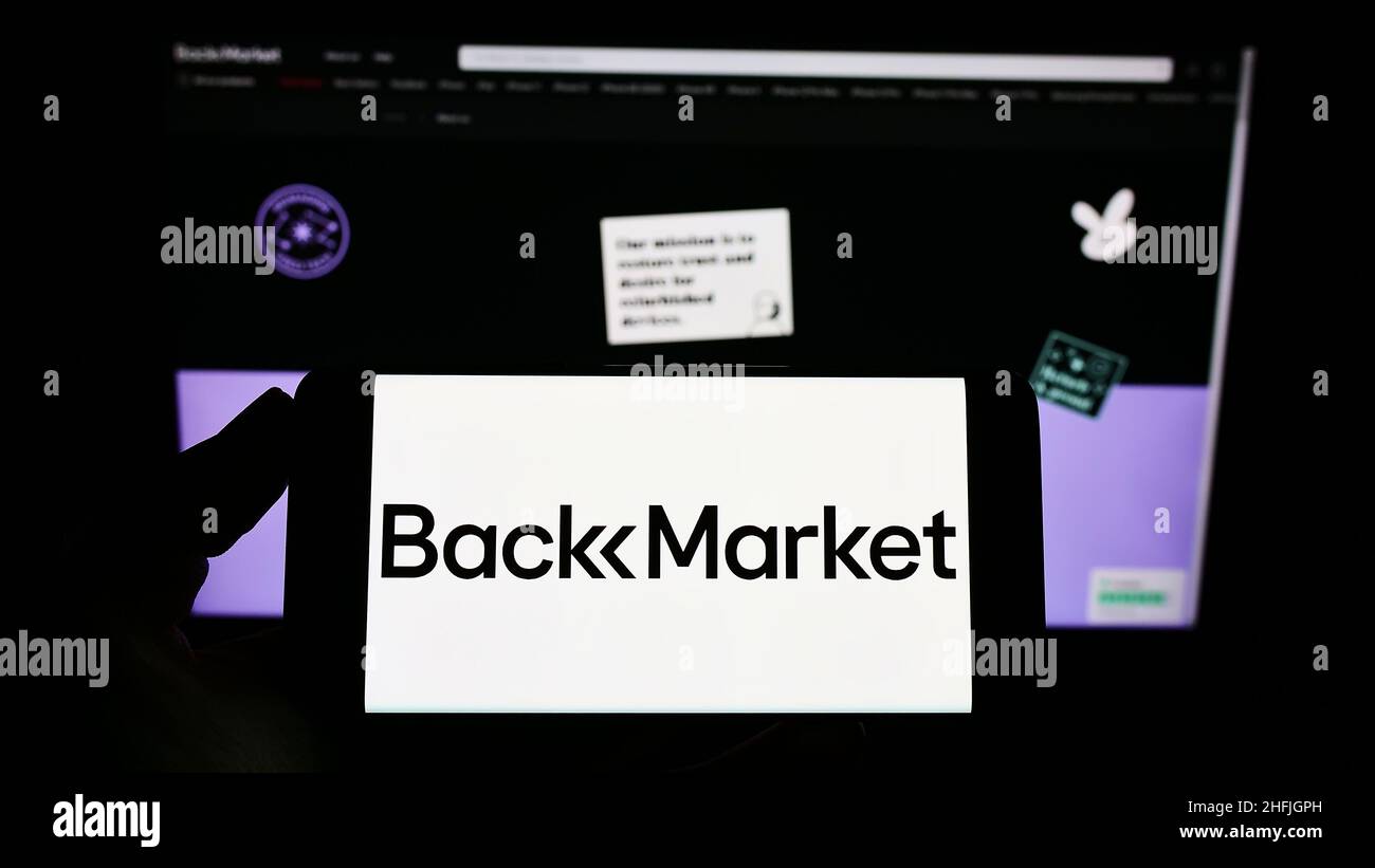 Persona che detiene il telefono cellulare con il logo della società francese di e-commerce Back Market (Jung SAS) sullo schermo di fronte alla pagina web. Mettere a fuoco sul display del telefono. Foto Stock