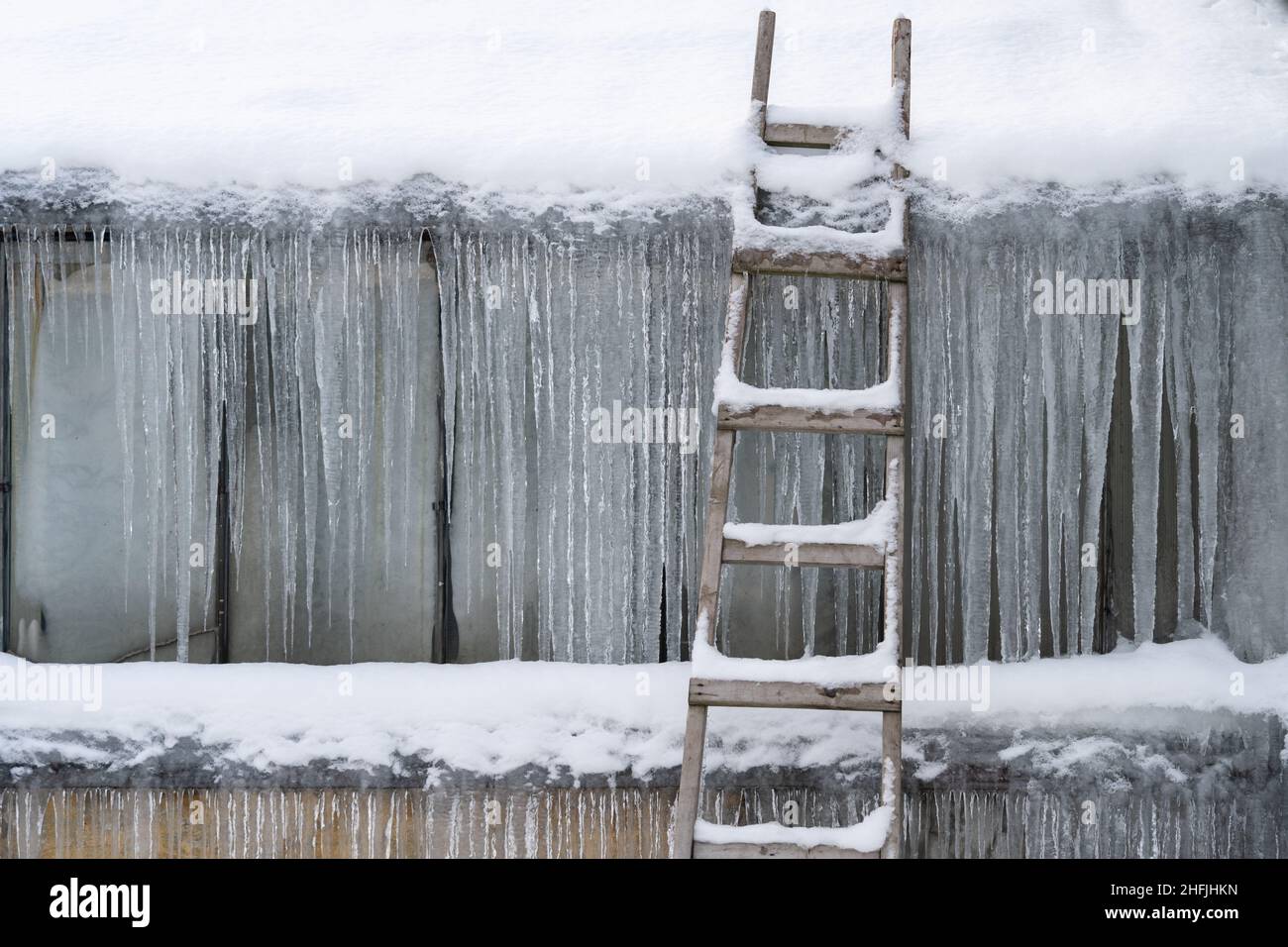 Vecchia scala di legno che surgela a parete coperta di ghiaccio congelato e ghiaccioli. Inverno freddo clima Foto Stock