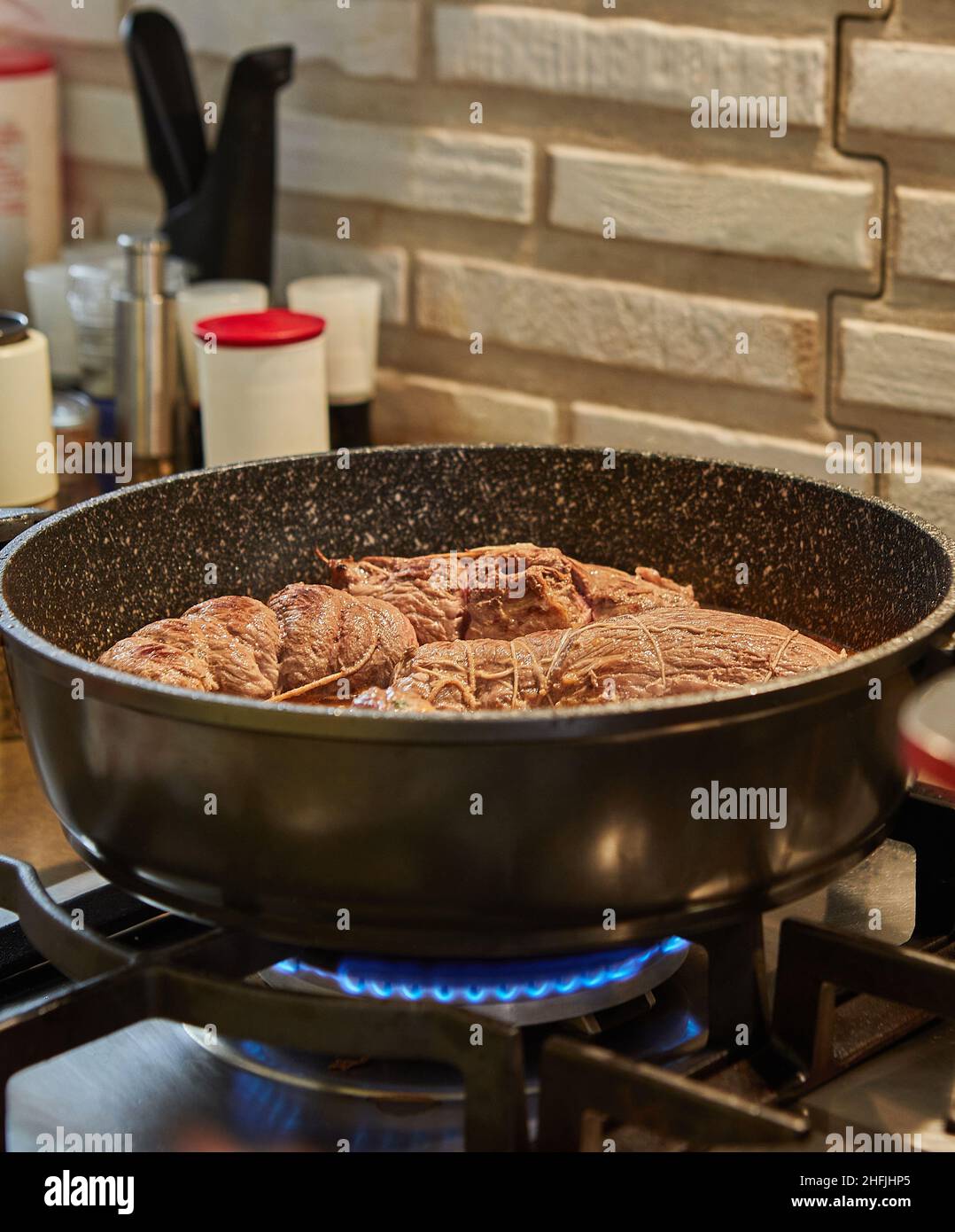 Lo chef frigge i panini di carne in una padella su una stufa a gas. Cucina gourmet francese Foto Stock