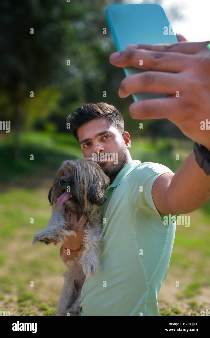 Ritratto di giovane con cane sul parco, prendendo selfie Foto Stock