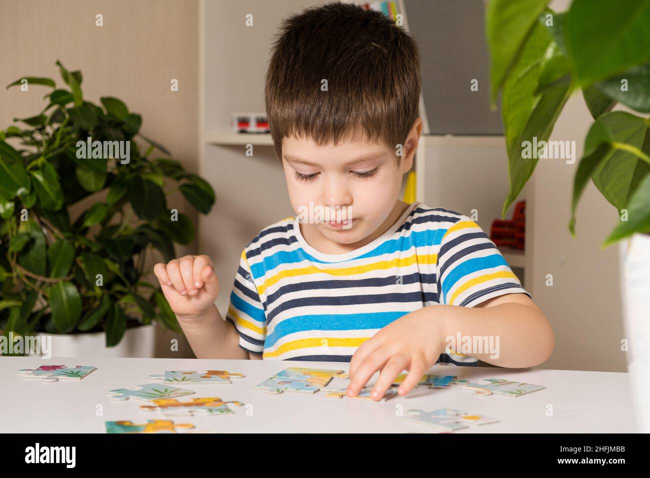 Un preschooler suona puzzle, mette insieme un'immagine Foto Stock