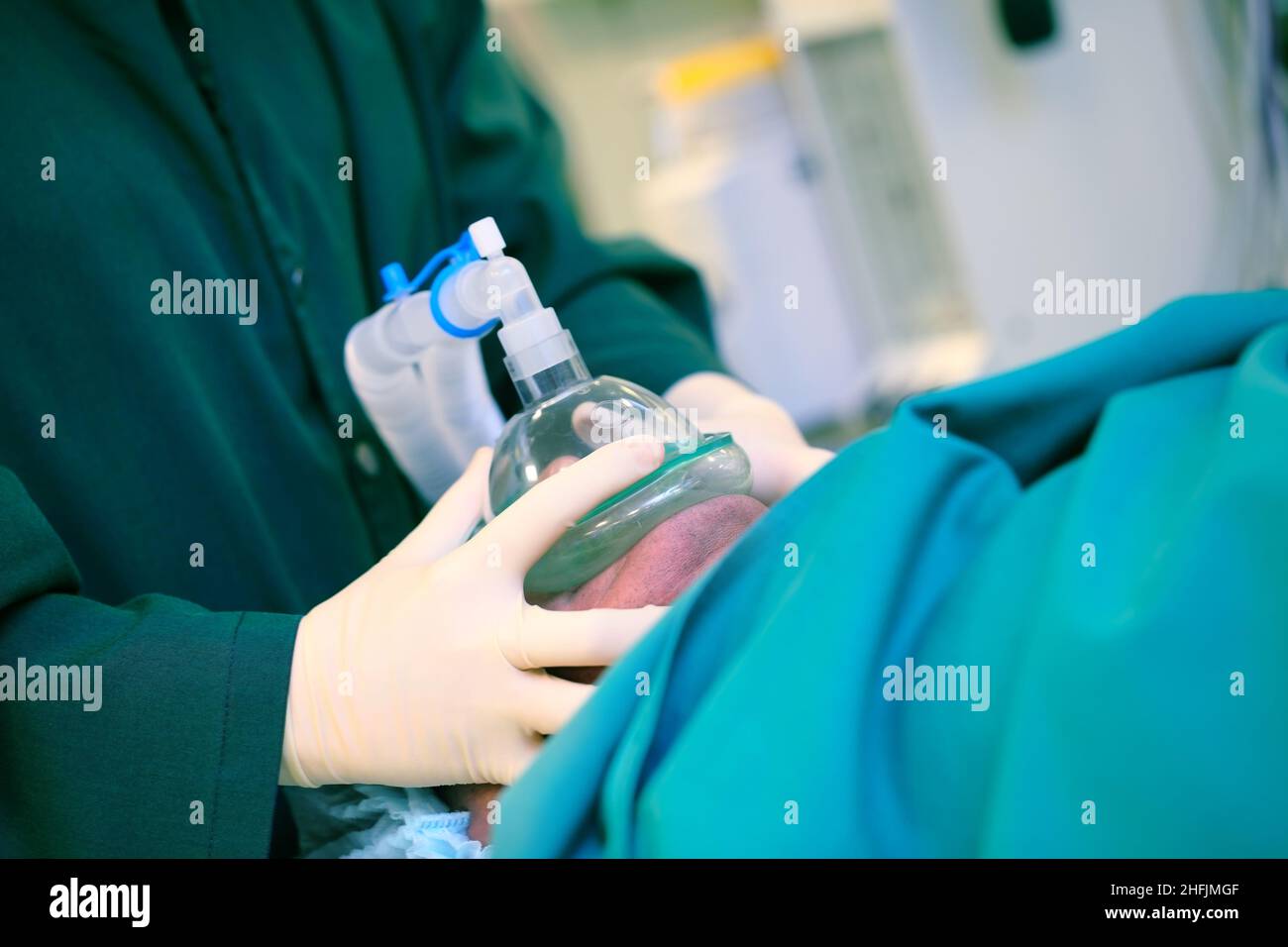 Il medico preme la maschera respiratoria artificiale sul viso del paziente, concetto del lavoro di un anestesista. Foto Stock