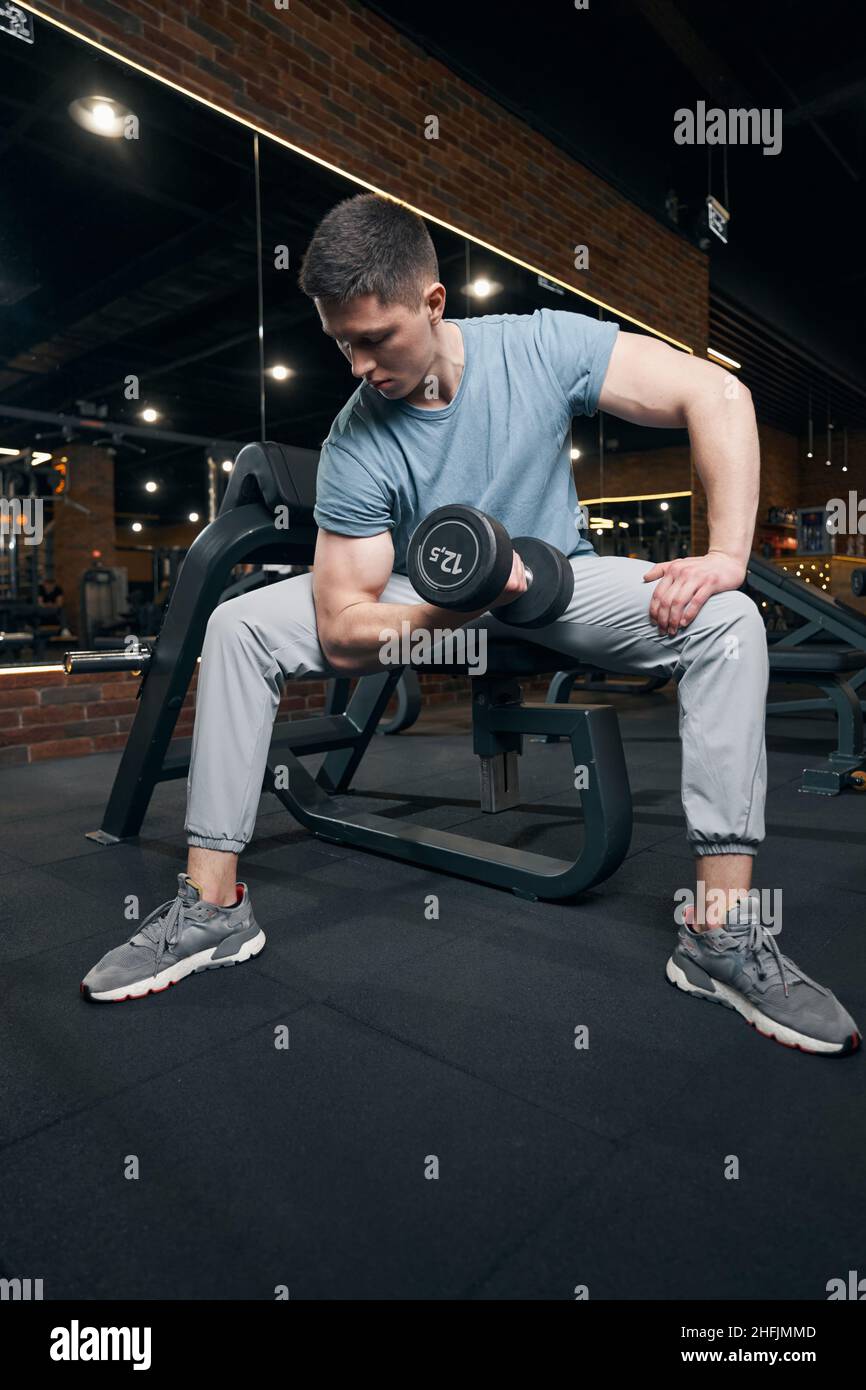 Atleta concentrato che esegue esercizio di sollevamento pesi in palestra Foto Stock