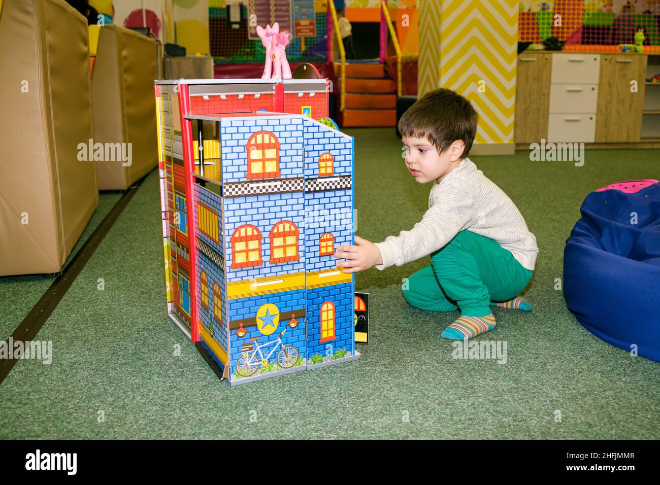 Un ragazzo di 4 anni gioca nella sala giochi del centro ricreativo per bambini con un grande castello giocattolo. Foto Stock