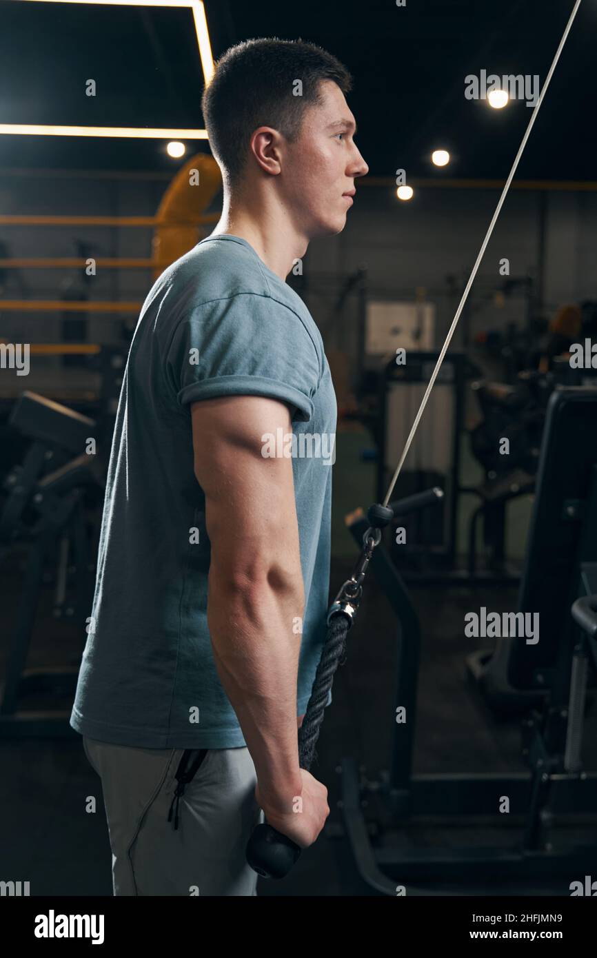 Atleta concentrato che esegue esercizio di resistenza su una macchina a cavo Foto Stock