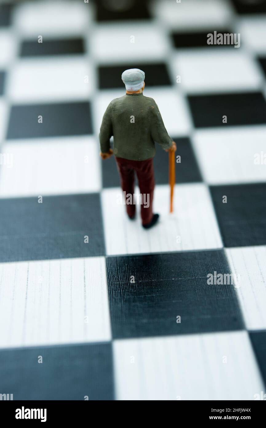 figurine in miniatura di un vecchio uomo con canna su scacchiera, invecchiamento e concetto di vecchiaia Foto Stock