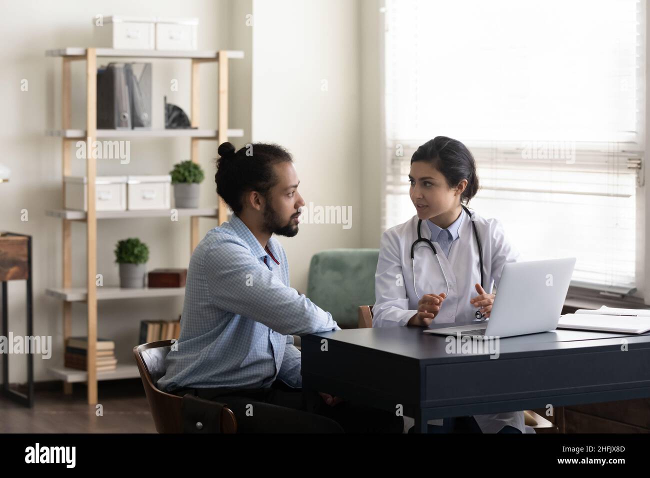 Focalizzato medico indiano consulenza paziente afroamericano. Foto Stock